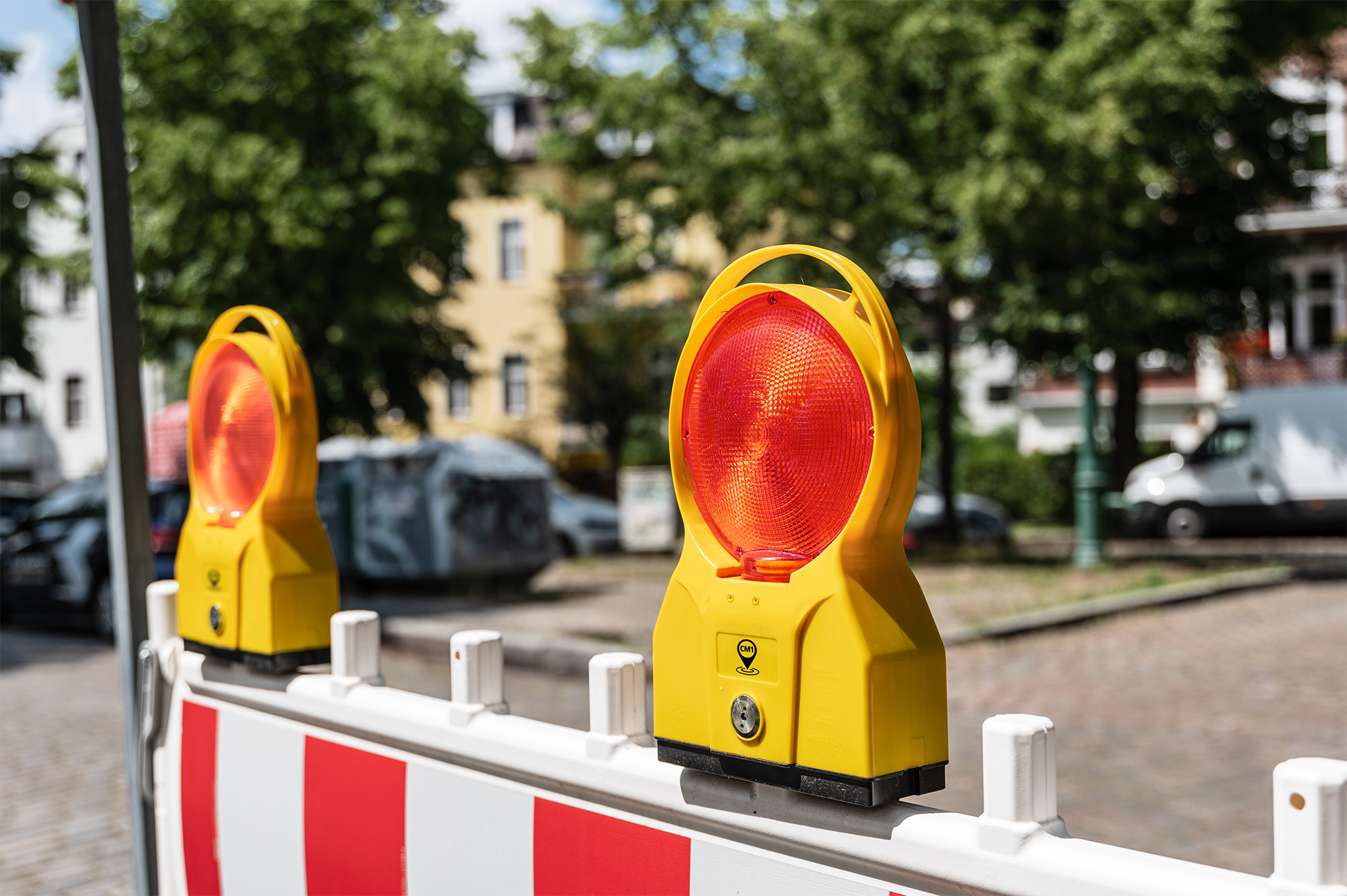 Baustellenleuchten an Absperrung auf einem gepflasterten Platz.